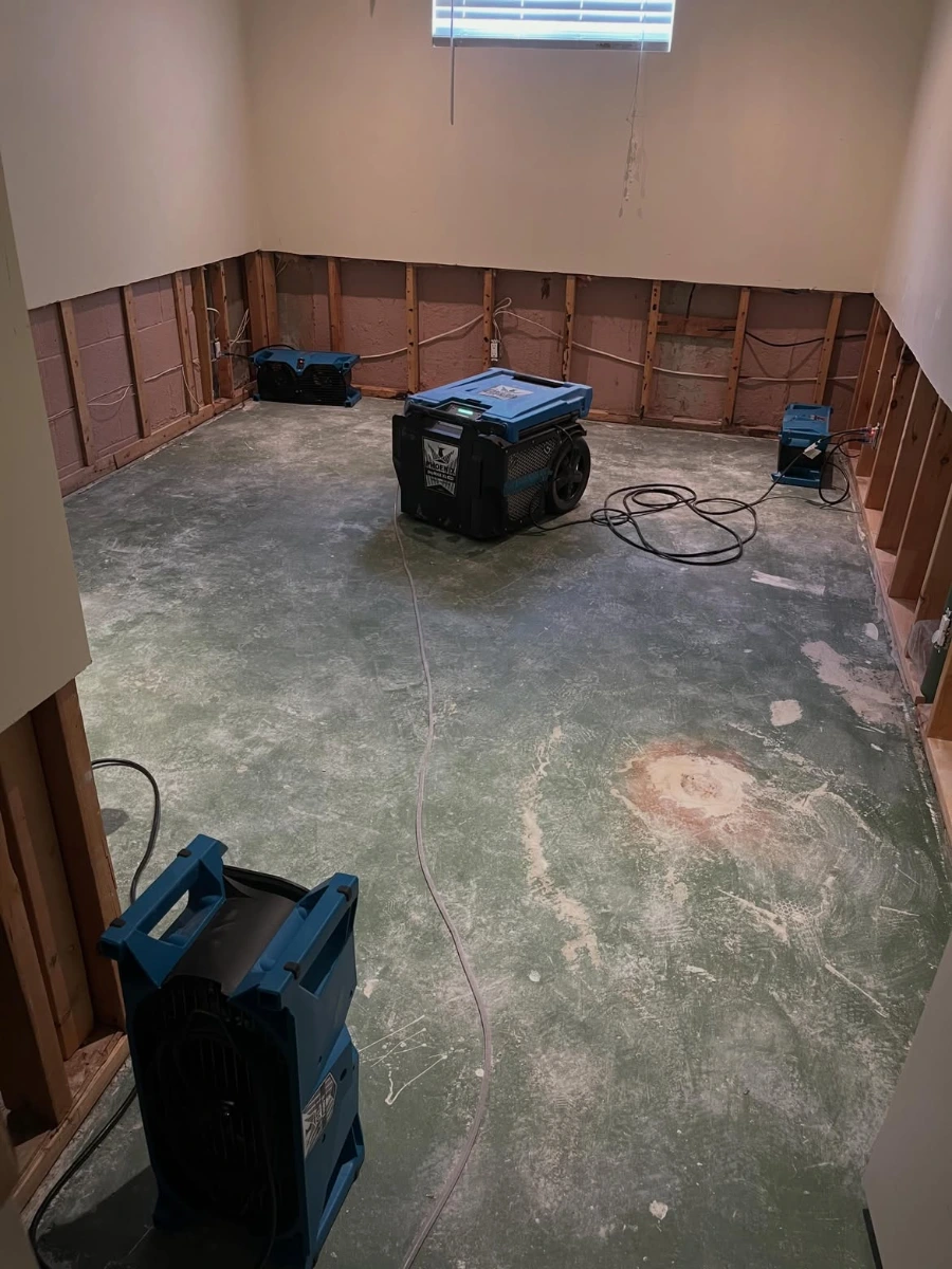 Basement room with flood-cut drywall and air movers drying a concrete floor after water damage in Minneapolis