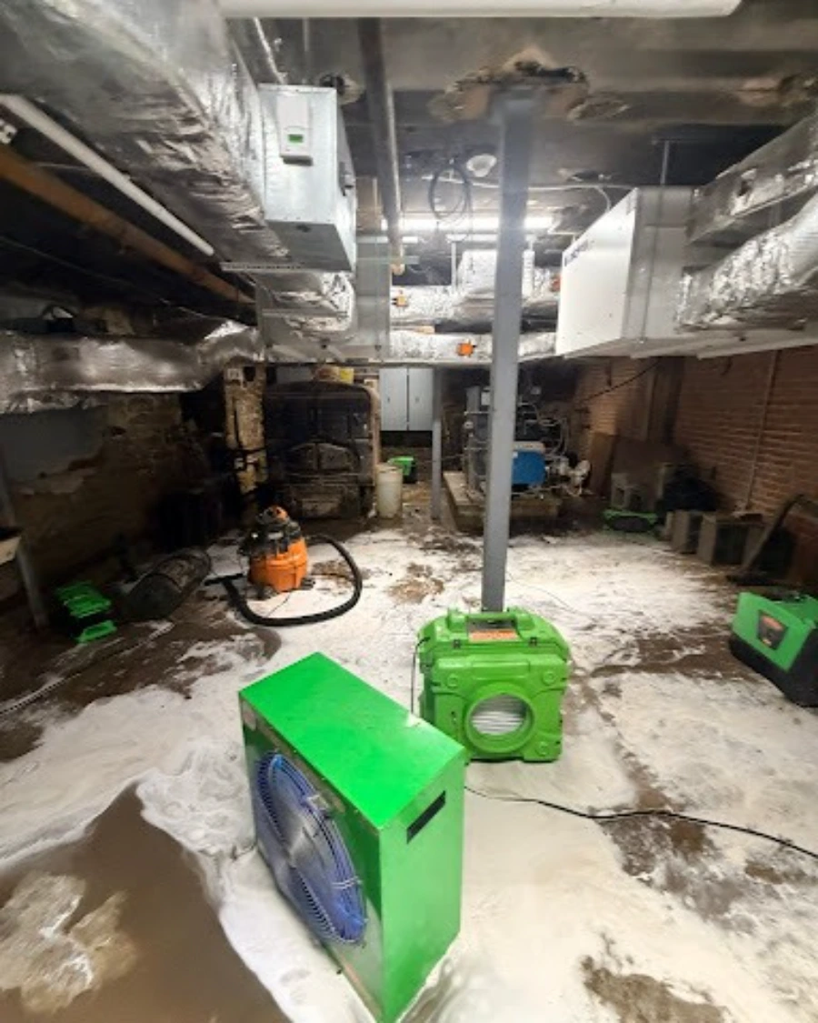 Flooded Minneapolis basement mechanical room with air movers and a wet vacuum during water extraction
