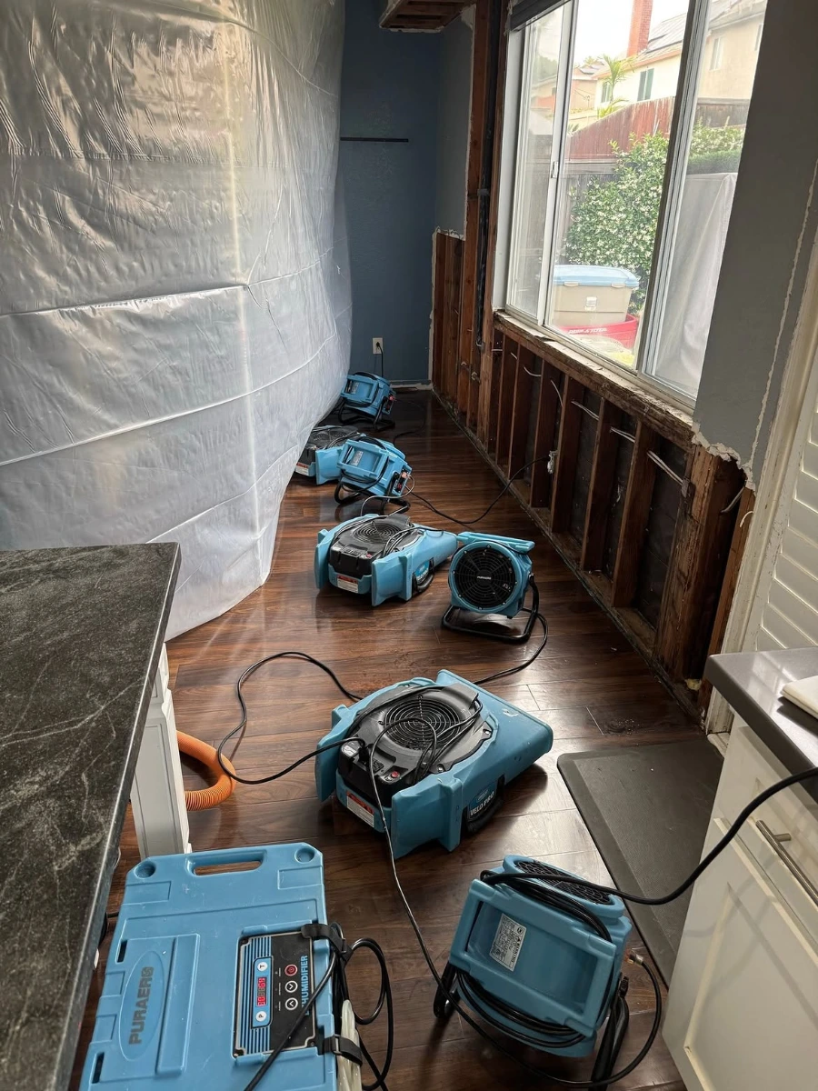 Industrial air movers and a dehumidifier drying a Minneapolis kitchen after water damage