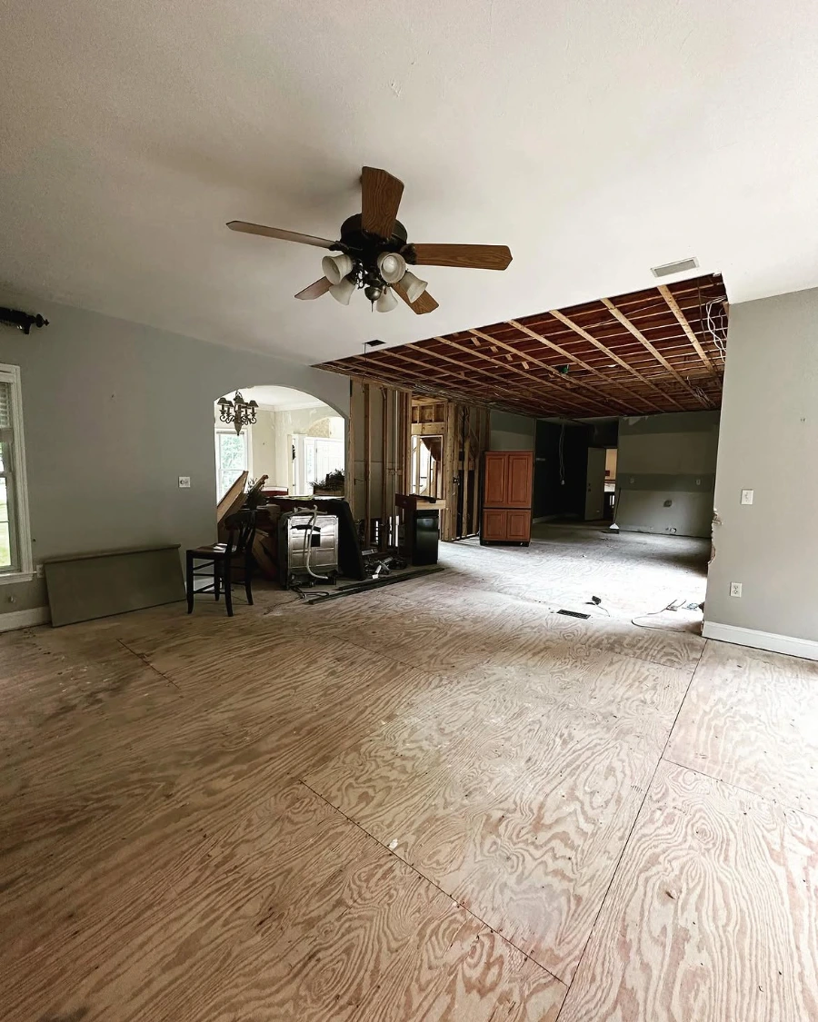 Second angle of a Minneapolis living room during water damage demolition with subfloor exposed