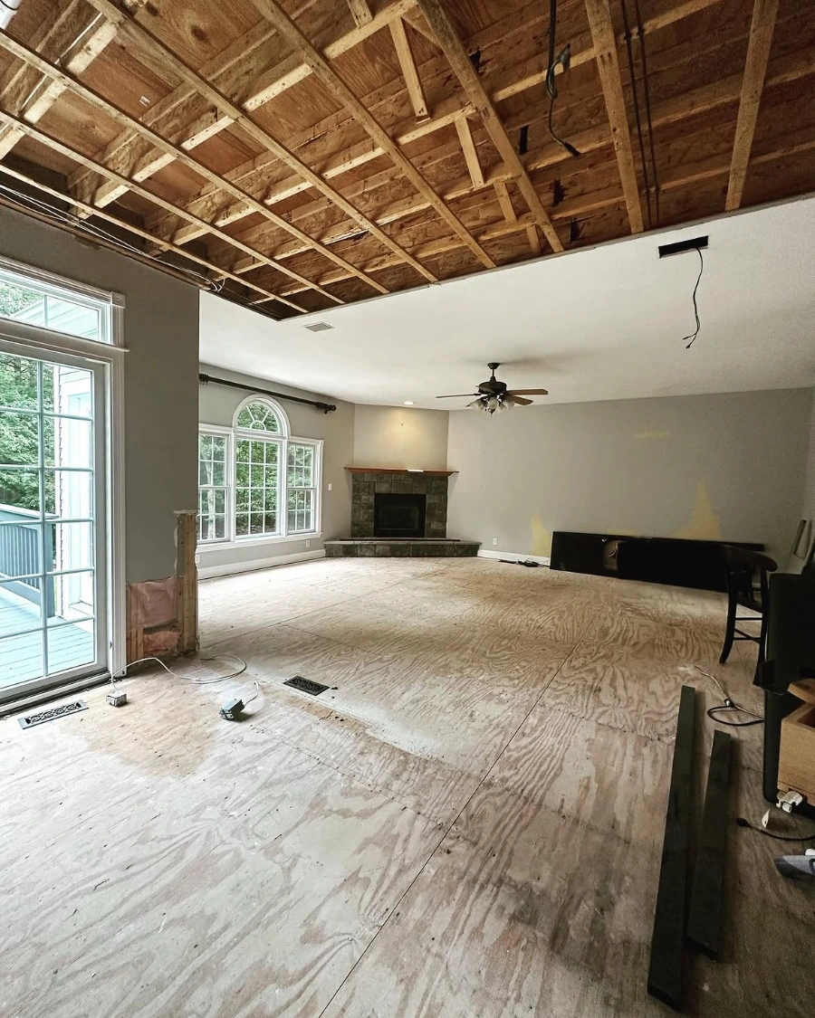 Minneapolis living room during water damage demolition with ceiling and subfloor exposed